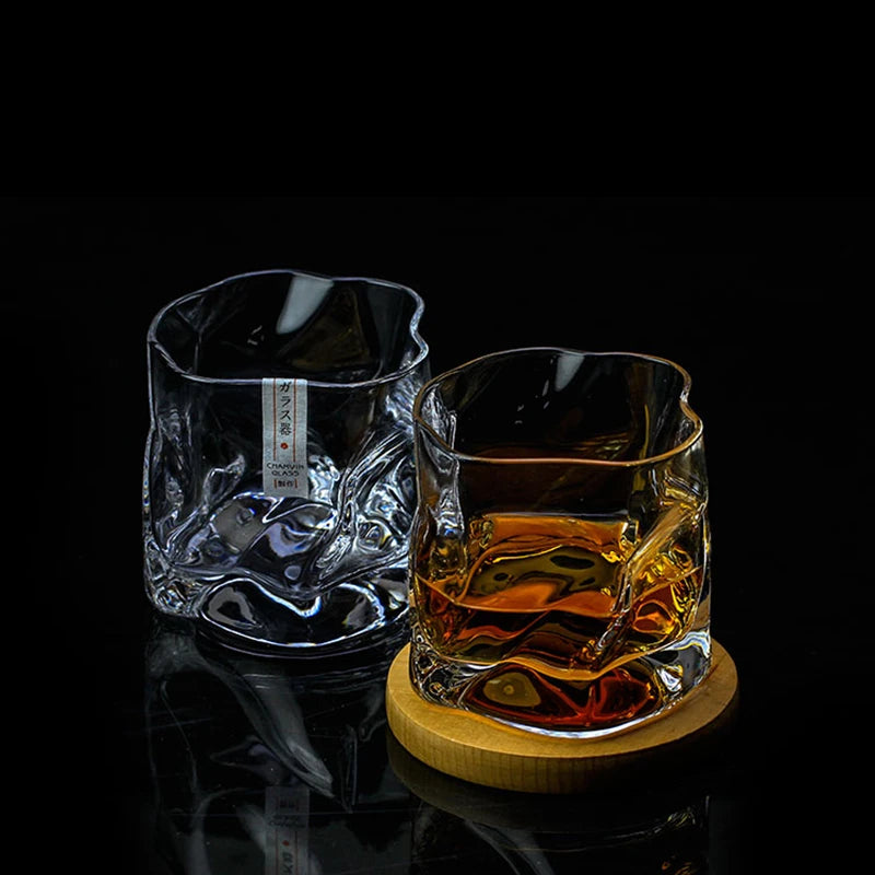 A glass of Lise Luxury Japanese Design Whiskey glass with a rich aroma on a wooden coaster with its packaging box in the background.
