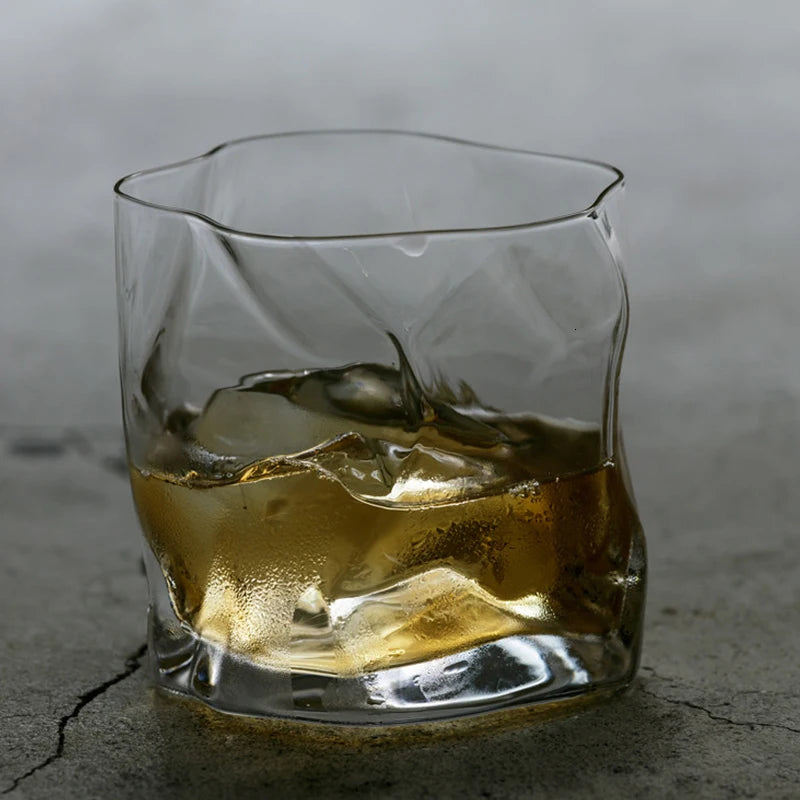 A glass of Lise Luxury Japanese Design Whiskey glass with a rich aroma on a wooden coaster with its packaging box in the background.