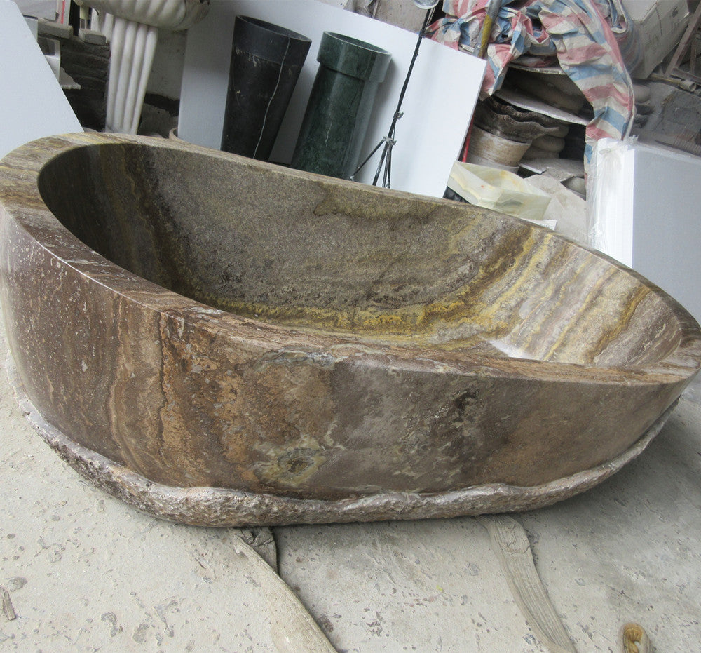 Lise Luxury's Down to Earth Marble Bath Tub with a natural, unfinished exterior sits elegantly on a concrete floor.