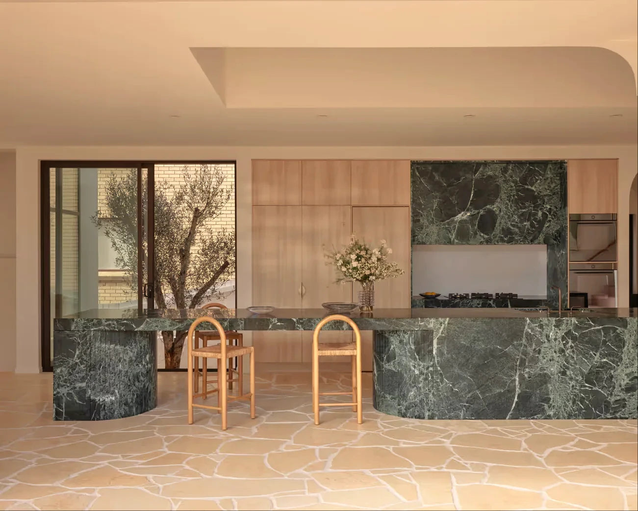 Green natural stone kitchen with sculptural marble island