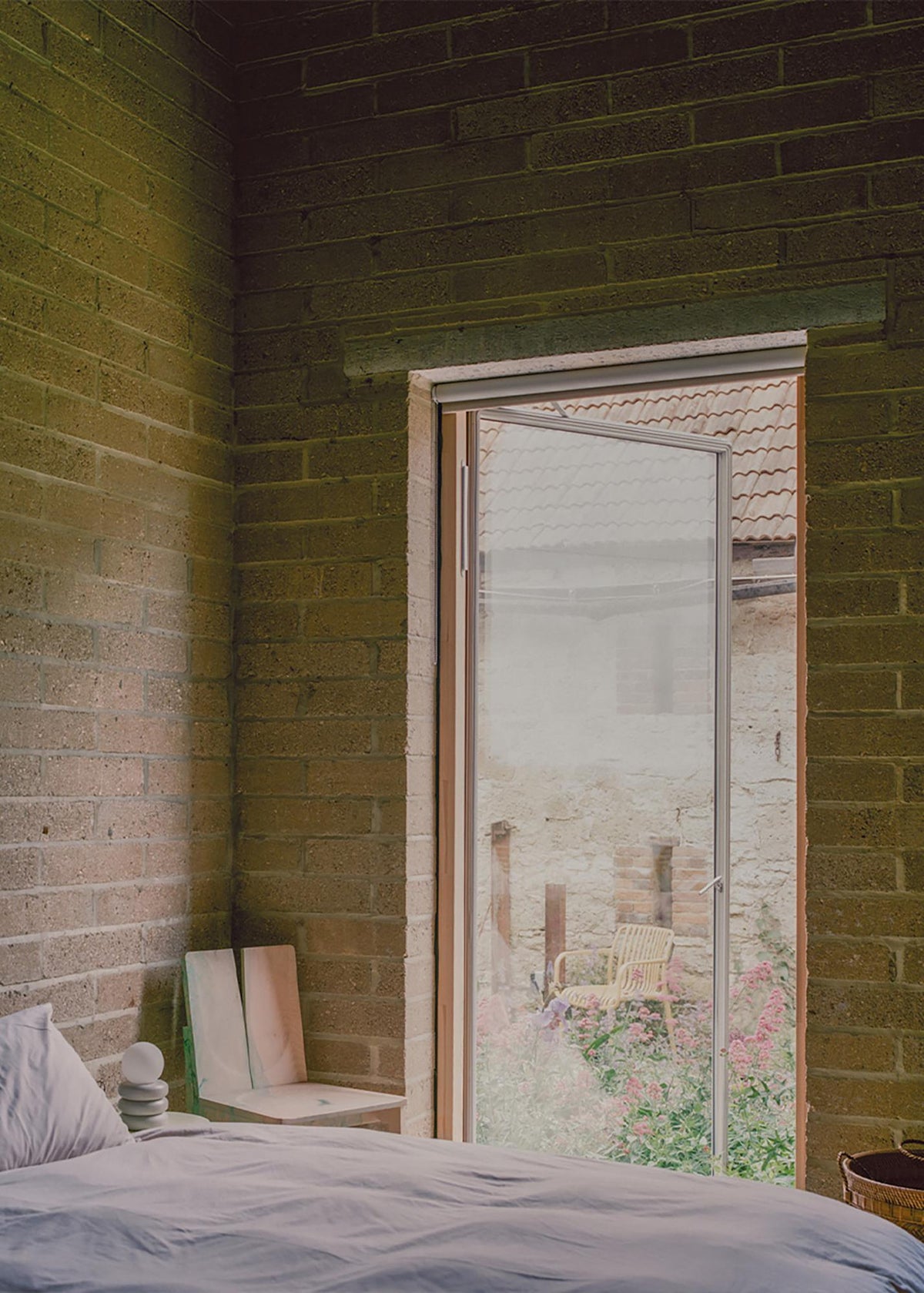 A bedroom window at South Barn frames planting and the neighbouring farm building.