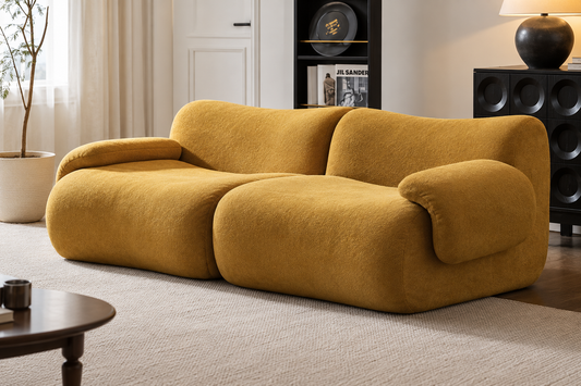 A modern modular sofa upholstered in a textured mustard yellow fabric, styled in a contemporary living room setting.