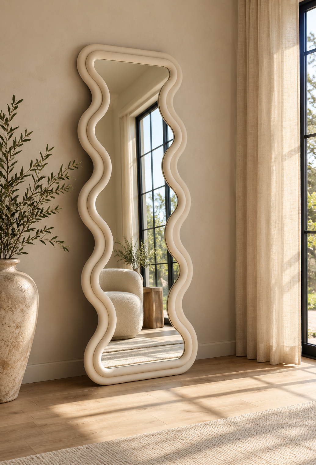[color:ivory] An ivory white tall floor mirror with a wavy, organic cream-colored frame leans against a beige wall in a sunlit room with wood floors, a large vase with greenery, and sheer curtains.