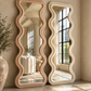 Ivory and rose full-length wavy mirrors with sculptural frames in a minimalist sunlit interior