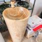 Luxury tall cylindrical standing marble basin sink by Lise Luxury with a bronze faucet, surrounded by various stone bathroom fixtures with customized options.