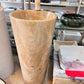Luxury tall cylindrical standing marble basin sink by Lise Luxury with a bronze faucet, surrounded by various stone bathroom fixtures with customized options.