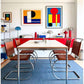 [color: cognac] A modern dining room setup featuring a rectangular table with a light wood top and chrome frame, surrounded by six chairs with brown leather seats and chrome frames. The room is decorated with mid-century modern furniture, including a red sideboard, colorful lamps, and abstract art prints on the wall.