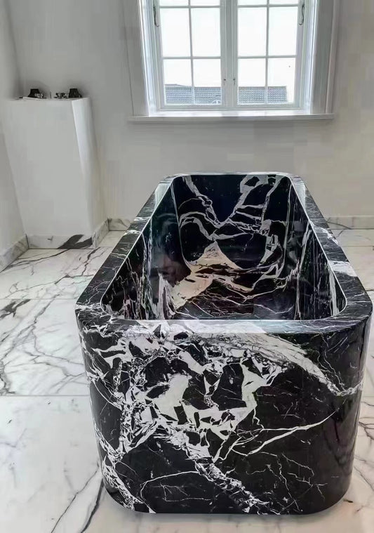 A Lise Luxury Black & White Marble Bath Tub with black and white veining, set in a bathroom with matching floor tiles.