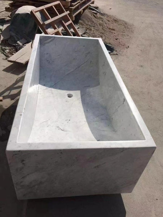 A Lise Luxury Rectangle Marble Bath Tub, with a rectangular design, displayed outdoors on a construction site.