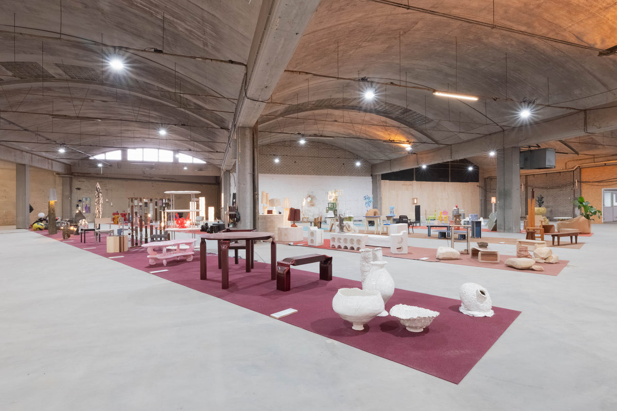 Wide view of Forward Furniture 2025, with furniture collections arranged on coloured carpets beneath a vaulted industrial ceiling