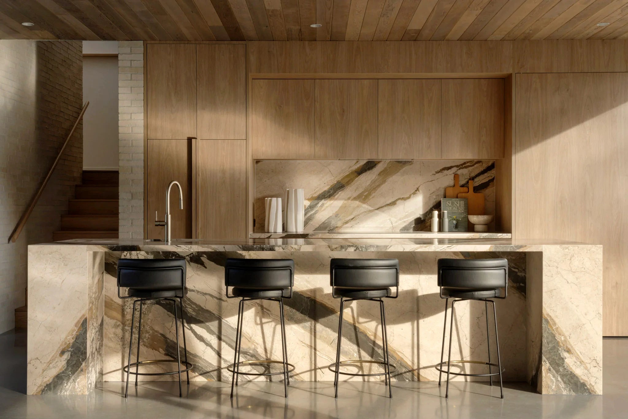 Architectural marble kitchen island with warm cabinetry