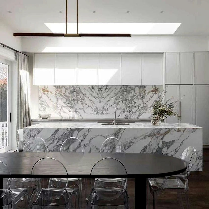 Bright Calacatta marble kitchen island and backsplash in a light contemporary interior