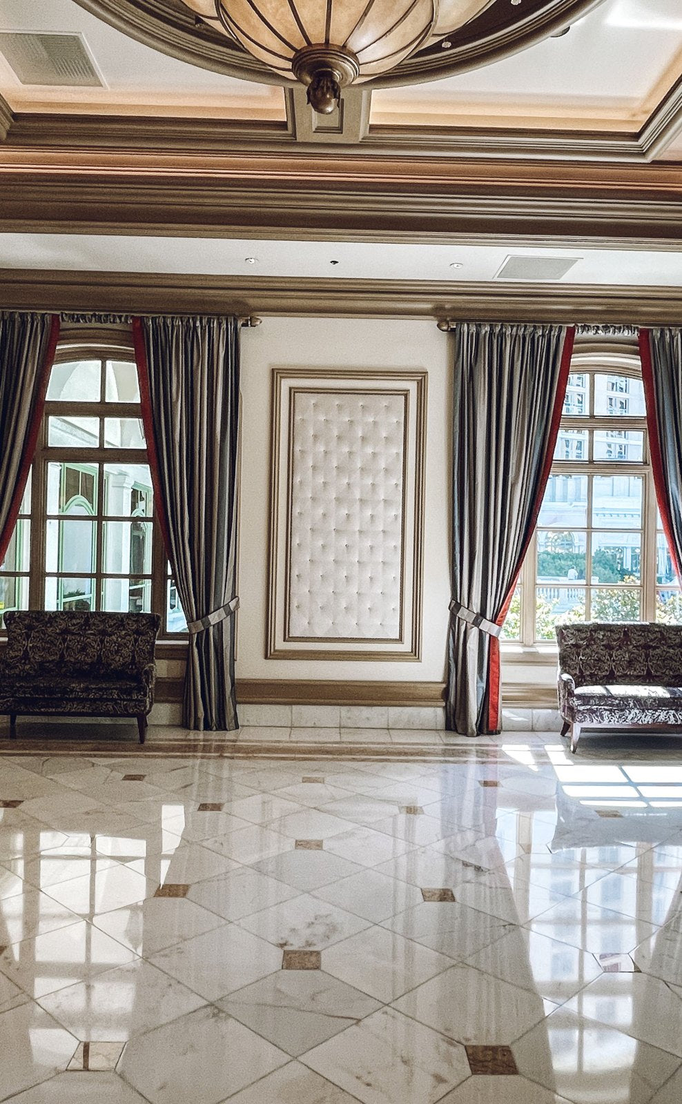 Hotel foyer with patterned flooring, tall doors and curtains