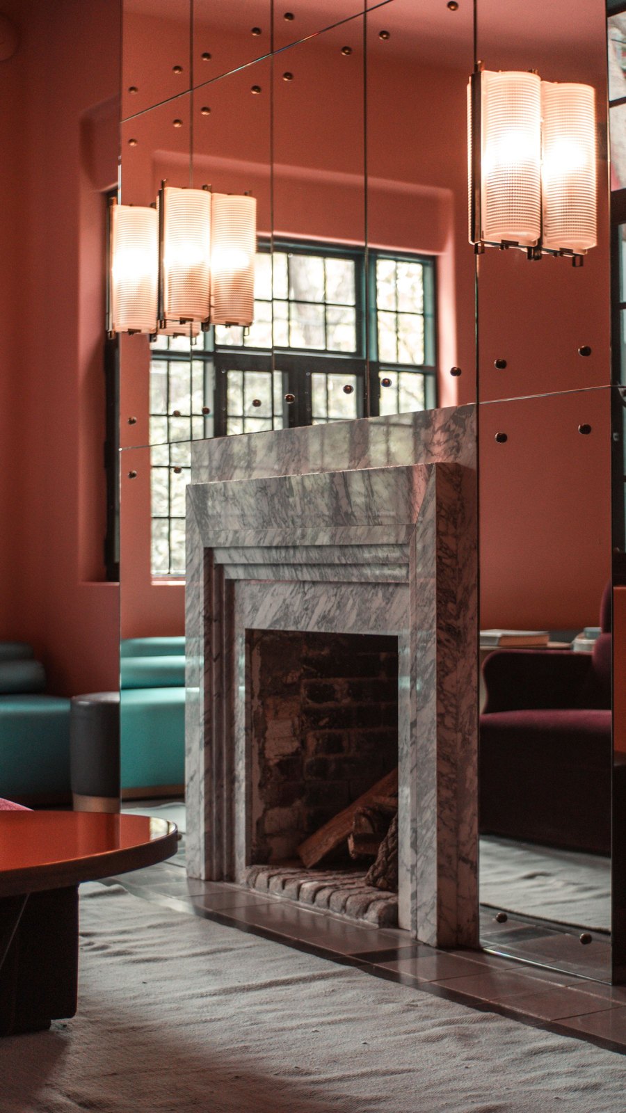Fireplace surround beside tall windows and mirrored wall panels