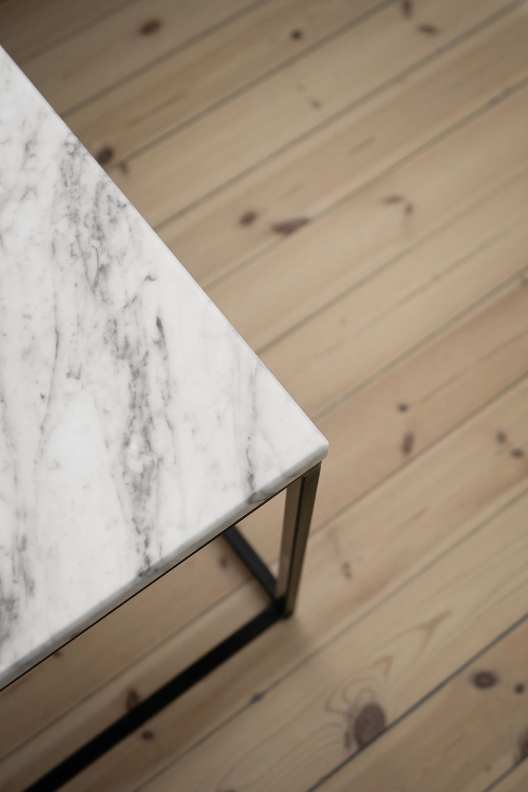 Close view of a pale veined table corner beside a timber floor