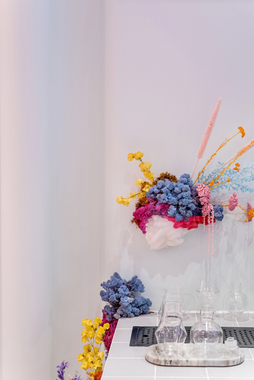 Clear glass vases and colourful flowers arranged on a pale tray