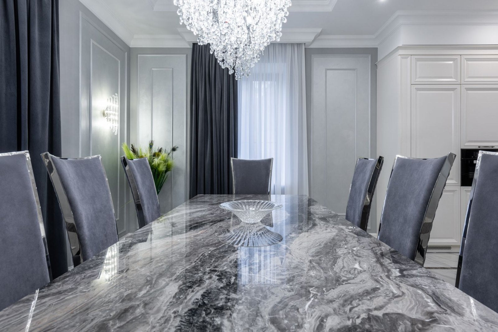 Veined dining tabletop with upholstered chairs in a grey interior