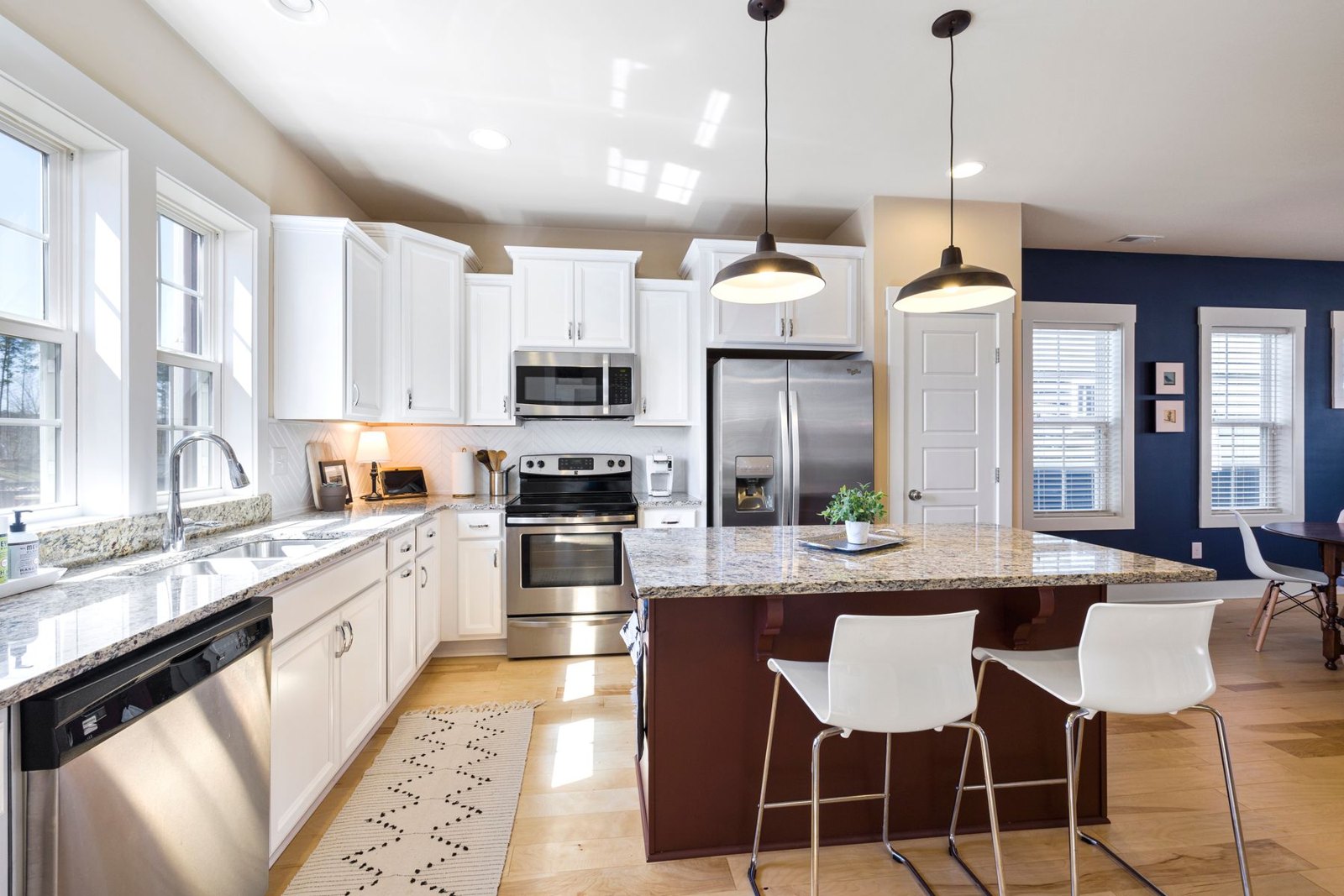 Open kitchen with central island, white cabinets and timber floor