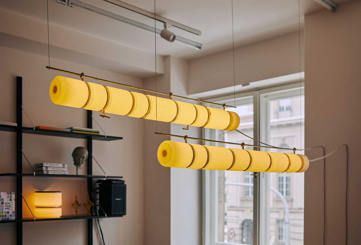 Two illuminated ribbed pendant lights by MOZI Studio