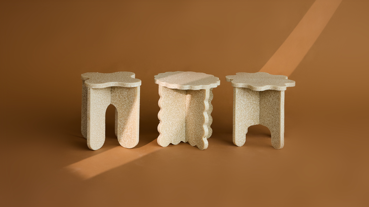 Three textured biopolymer stools by MOZI Studio against a warm brown backdrop